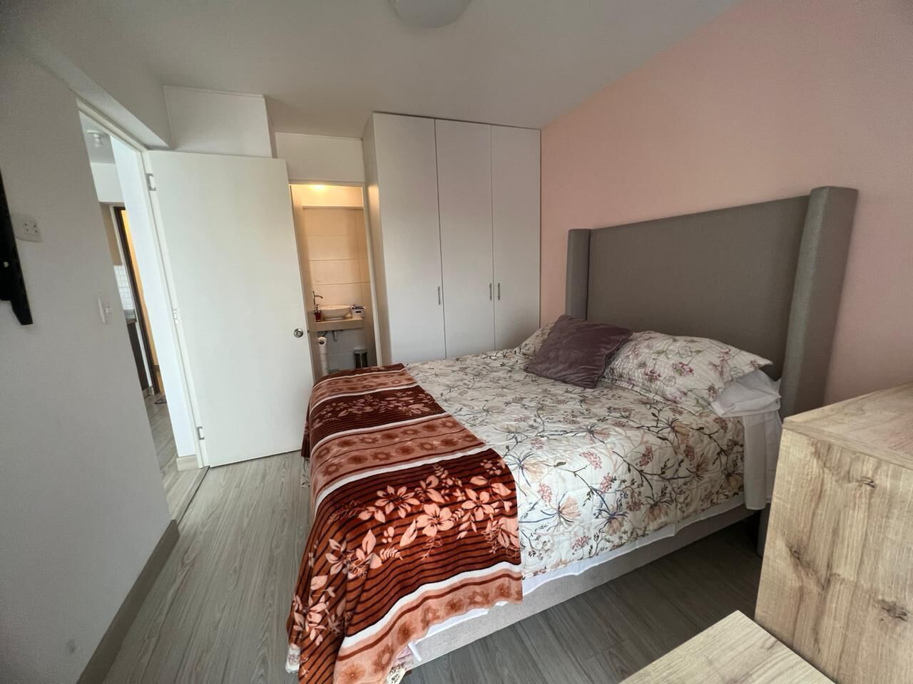 Une chambre à coucher comprenant un lit, une armoire, une table de chevet et une porte donnant sur une salle de bain.