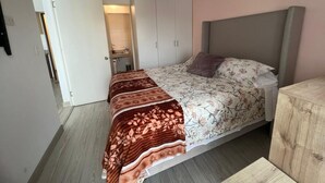 Una camera da letto con un letto, un armadio, un comodino e una porta che dà su un bagno.