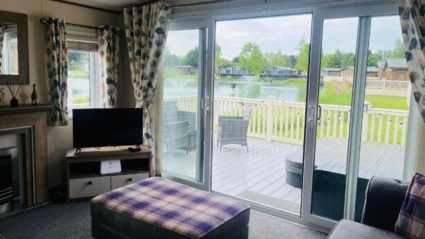 A room with a bed, a TV on a stand, a fireplace, and large sliding glass doors to a deck.
