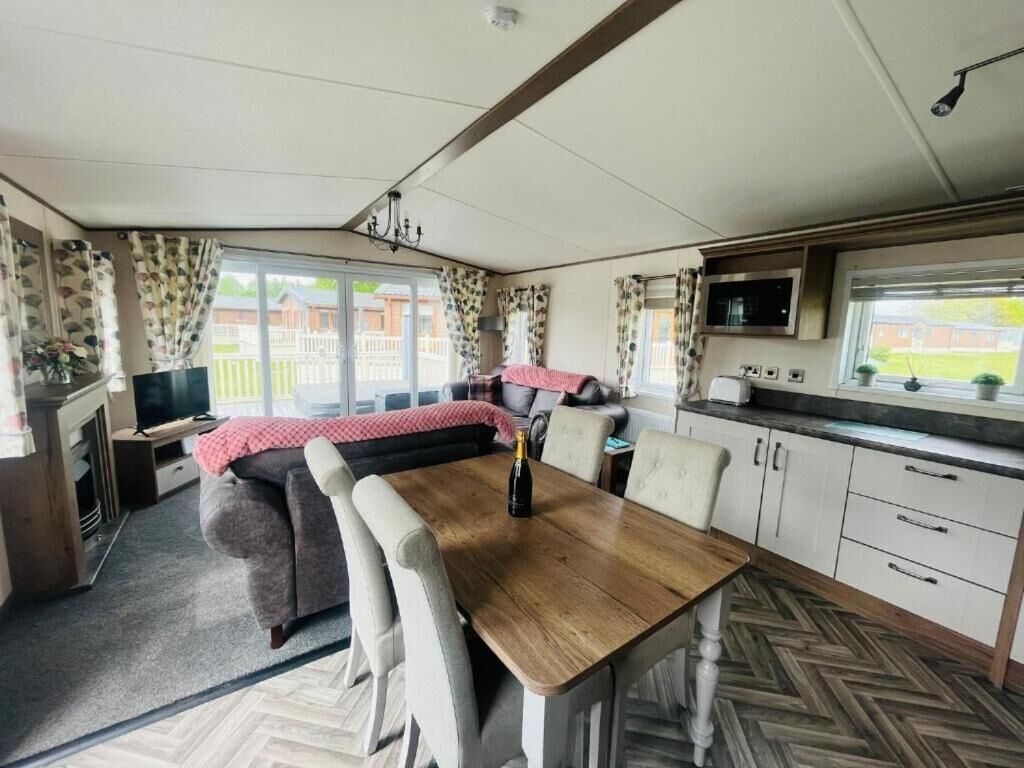 Un intérieur de camping-car compact comprenant un coin repas, un coin cuisine et une grande fenêtre donnant sur un quartier résidentiel.