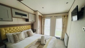A hotel room with a large bed, built-in cabinets, a television, and a window with curtains.