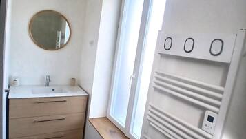 Une petite salle de bain moderne avec un lavabo blanc, un miroir et une fenêtre.