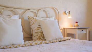 A neatly made bed with a headboard, pillows, and a bedside table with a lamp.