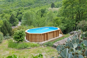 A hot tub surrounded by lush greenery and a wooden deck.