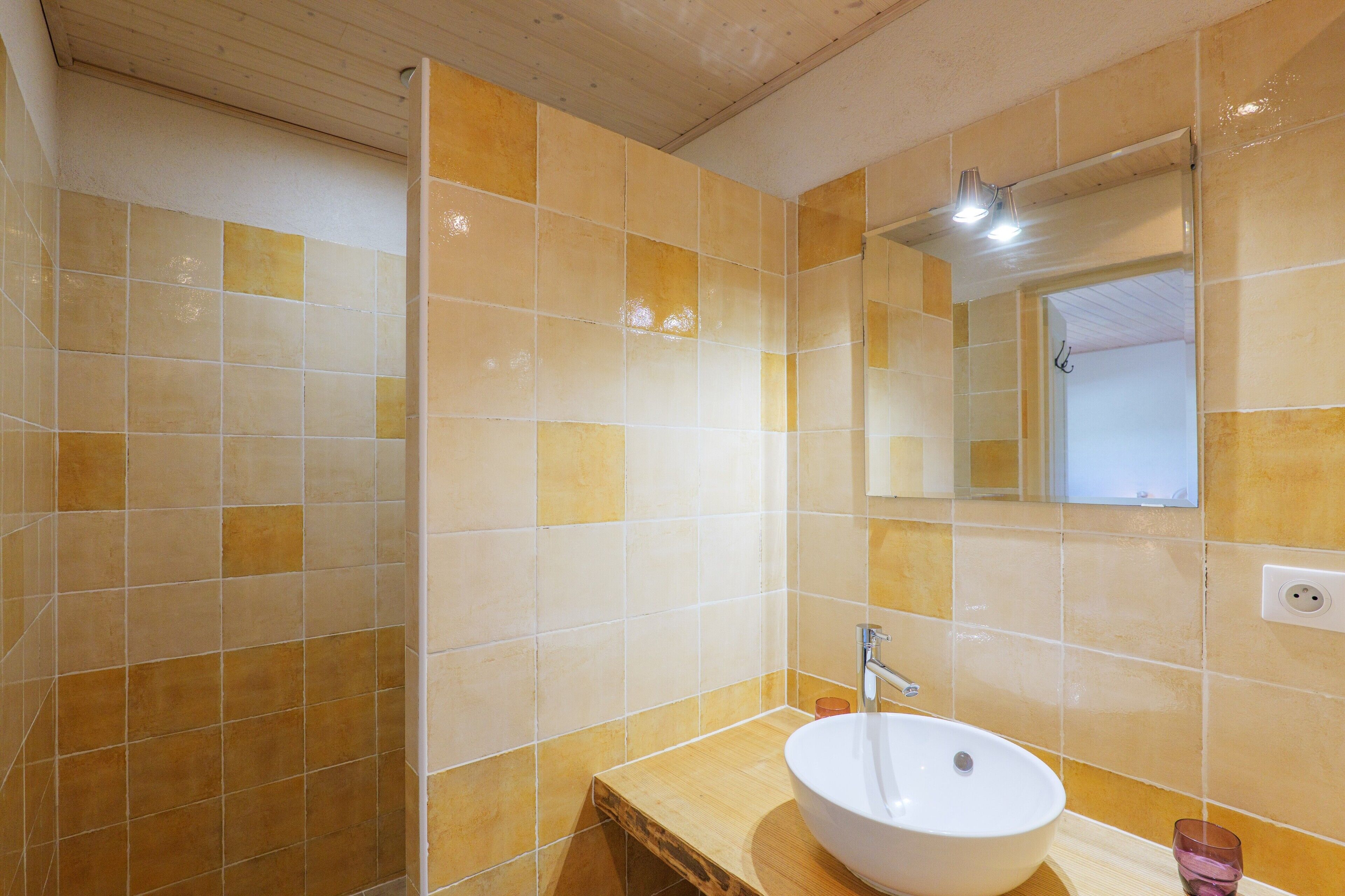 Een badkamer met een houten wastafelmeubel, een witte wastafel en een spiegel.