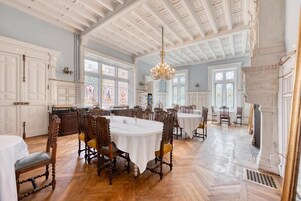A spacious dining area with high ceilings and ornate chandeliers.