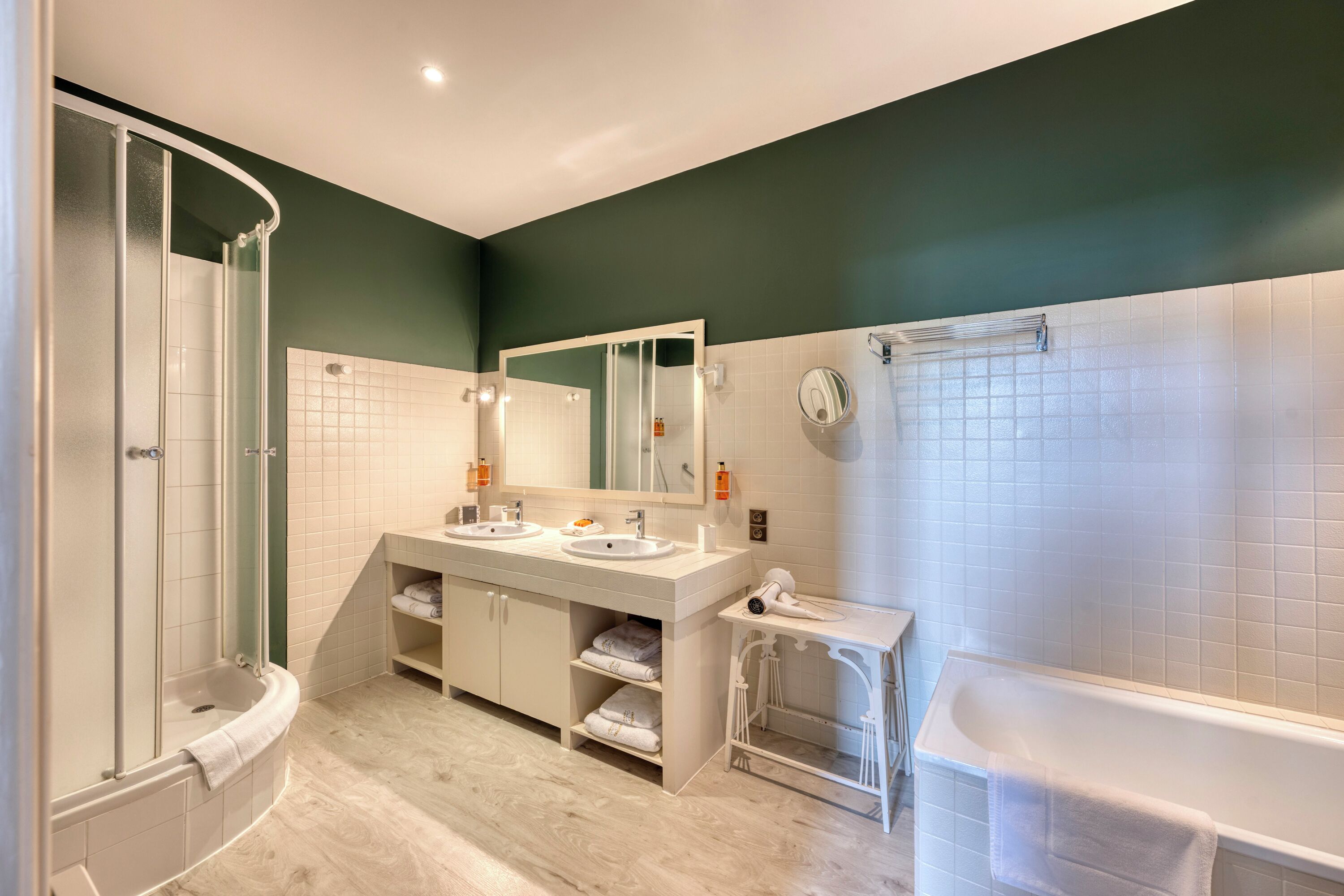 A modern bathroom with a shower, two sinks, a large mirror, and a bathtub.