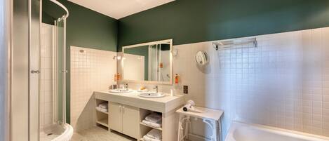 A modern bathroom with a shower, two sinks, a large mirror, and a bathtub.