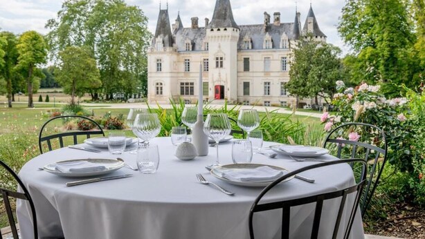 A table set outdoors with a view of a historic building. - Château Optical Center (Nieuil)