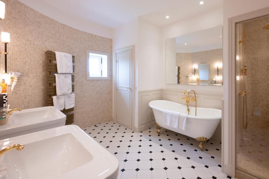 Un baño con dos lavamanos, una bañera y una ducha.