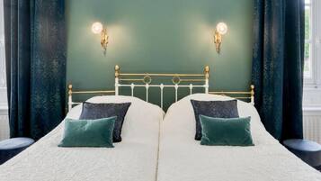 A double bed with a white and green color scheme, two wall-mounted lights, and a green wall.