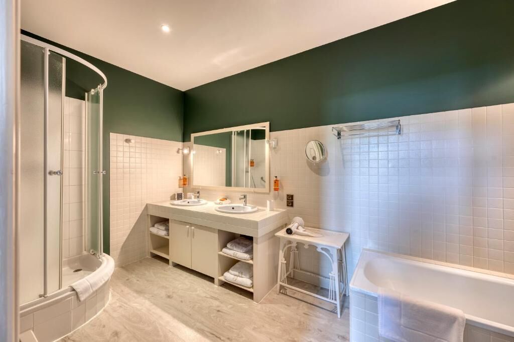 Un baño moderno con ducha, dos lavamanos, un espejo grande y una bañera.