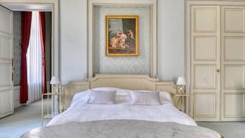 A bedroom with a large bed, a painting above the bed, and a wardrobe with a mirror.