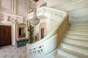 A grand staircase with ornate white railings and a chandelier.