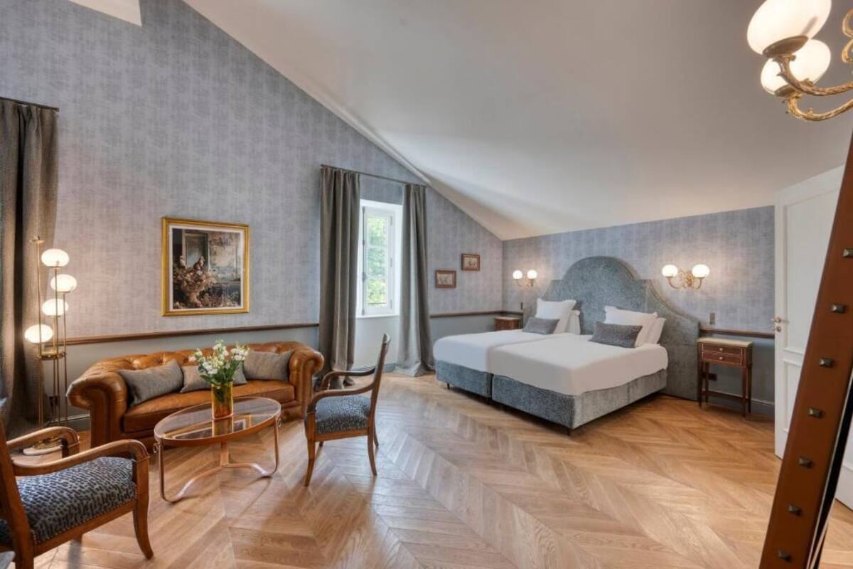 Een hotelkamer met een groot bed, een bank, een stoel, een klein tafeltje en een schilderij aan de muur.