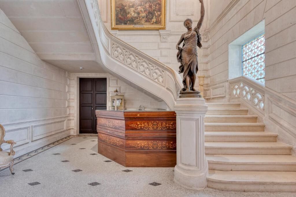 Una imponente escalera con una estatua, un escritorio de madera y una puerta.