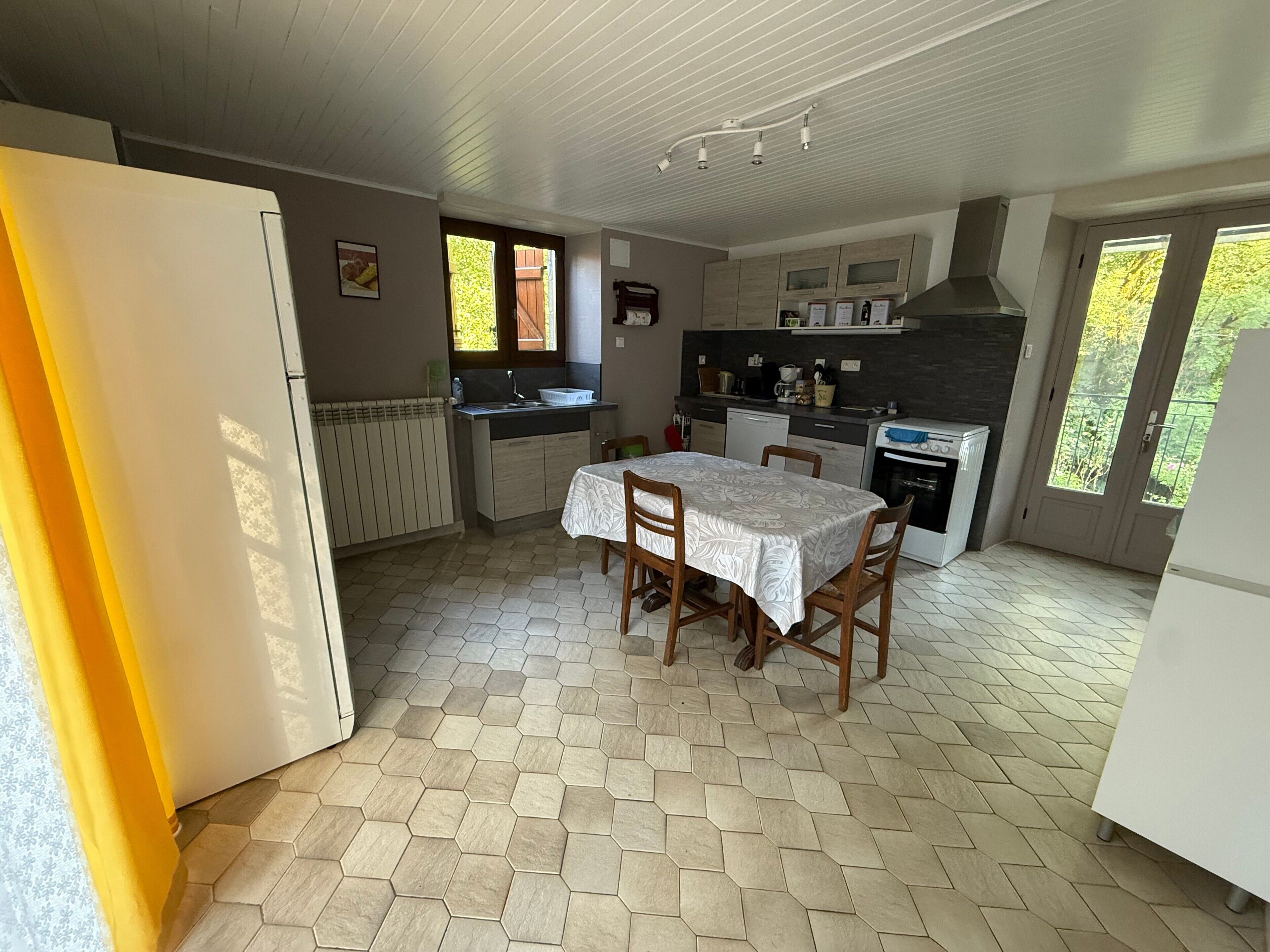 A kitchen with a dining table, chairs, a refrigerator, a stove, and a window.