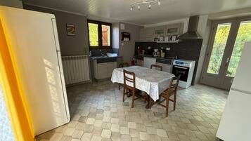 A kitchen with a dining table, chairs, a refrigerator, a stove, and a window.