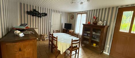 A dining area with a round table, chairs, a wooden cabinet, and a television.