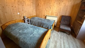 Ein Schlafzimmer mit zwei Betten, einem Sessel, einem Heizkörper und einem kleinen Tisch.