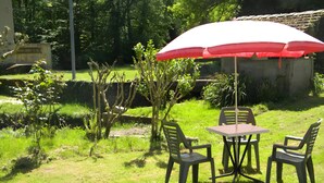 Ein Sitzbereich im Freien mit Tisch und Stühlen, einem roten Sonnenschirm und einem Garten.