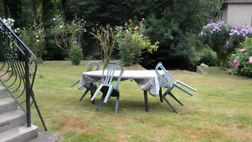 A garden with a table and chairs, surrounded by trees and flowers.