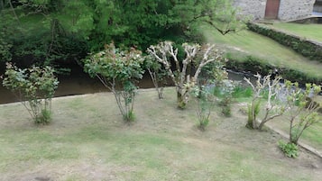 A grassy area with trees and a stone building with a door.