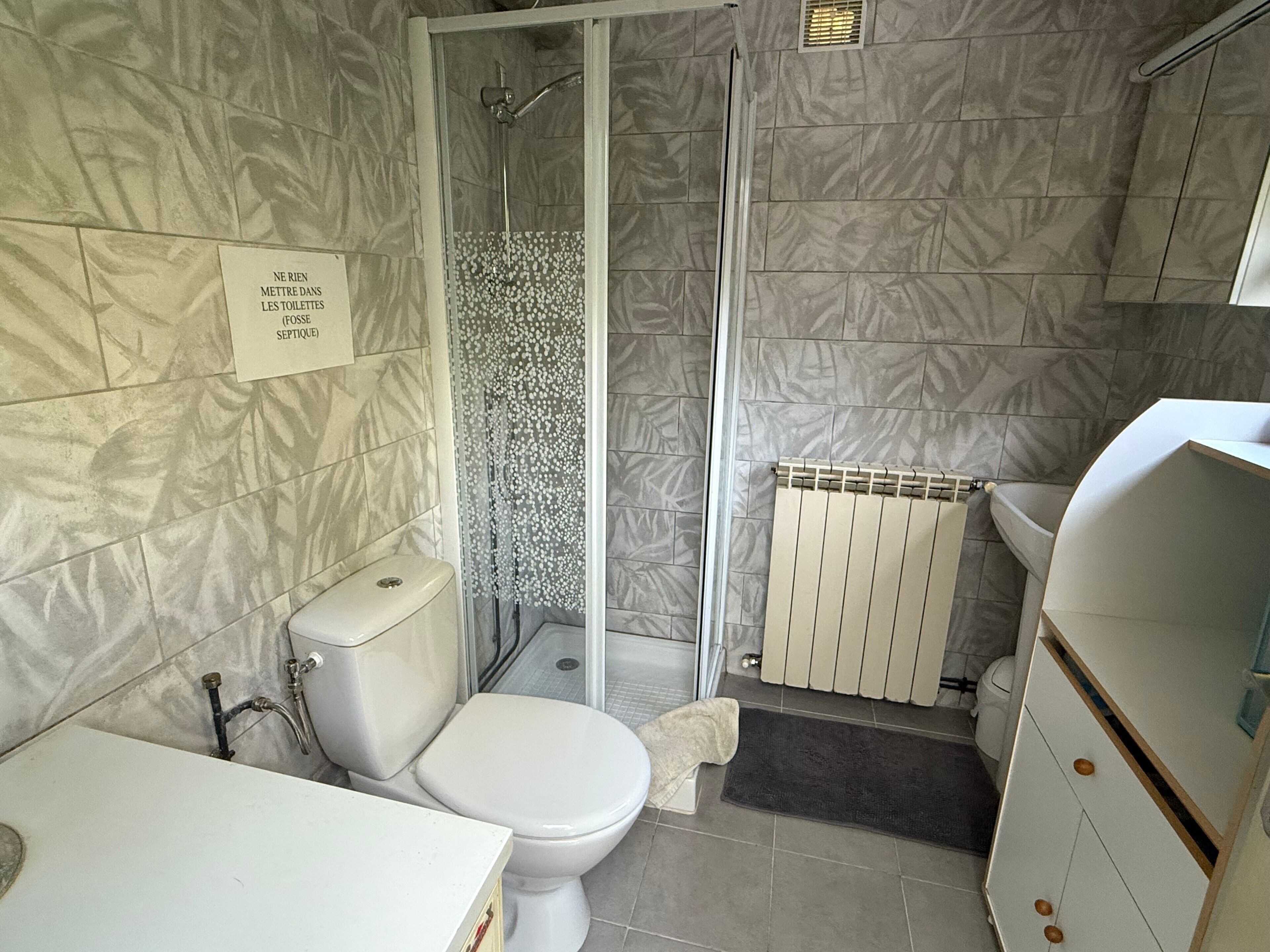 A bathroom with a toilet, shower, and sink.