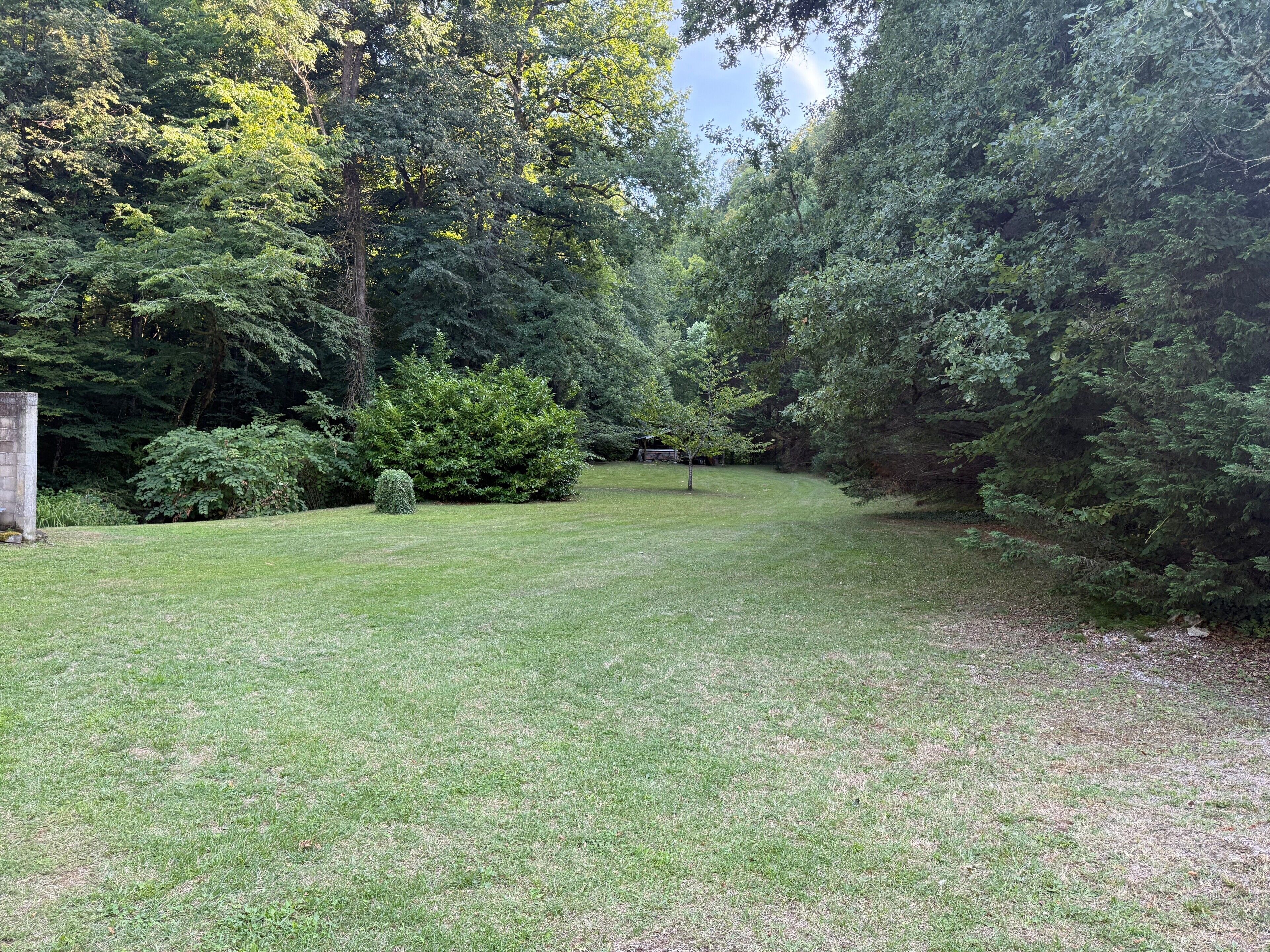 Een gazon met bomen en een stenen gebouw.