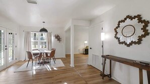 Een ruime kamer met een eethoek, een grote spiegel en een radiator.