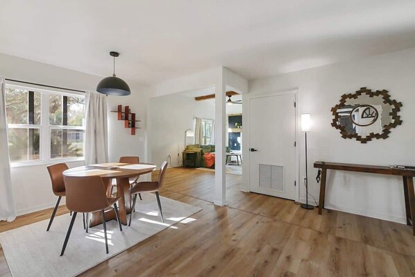 A modern dining area with a round table and chairs, a pendant light, and a wall clock. - One Acre Peaceful Property | King Bed, Game Room | (Gainesville)