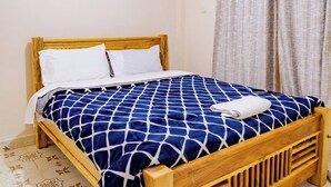 Una cama individual con estructura de madera, una colcha estampada y un cabecero.