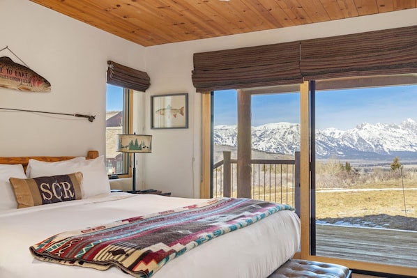 Une chambre avec un grand lit, une fenêtre donnant sur les montagnes, un poisson décorant le mur et une pancarte sur laquelle on peut lire : « Bienvenue au bord du lac ».