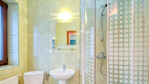 A bathroom with a toilet, sink, and glass-enclosed shower. - Dom Wczasowy Na Kamiencu (Białka Tatrzańska)