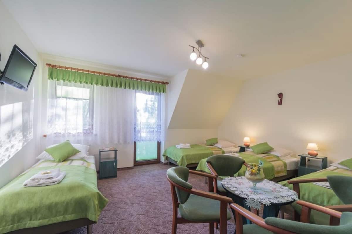 A room with two beds, a chair, a table, and a TV.