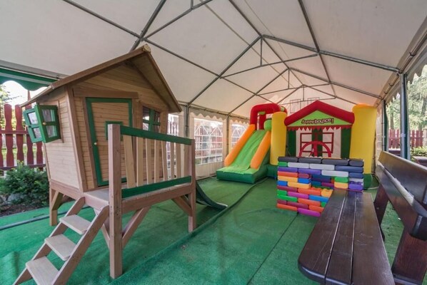 A play area with a wooden playhouse, a slide, and colorful blocks.