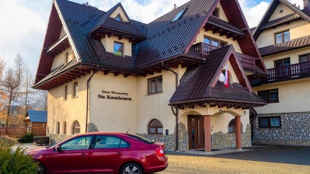 A building with a traditional architectural style, featuring multiple gabled roofs and a stone facade. - Dom Wczasowy Na Kamiencu (Białka Tatrzańska)