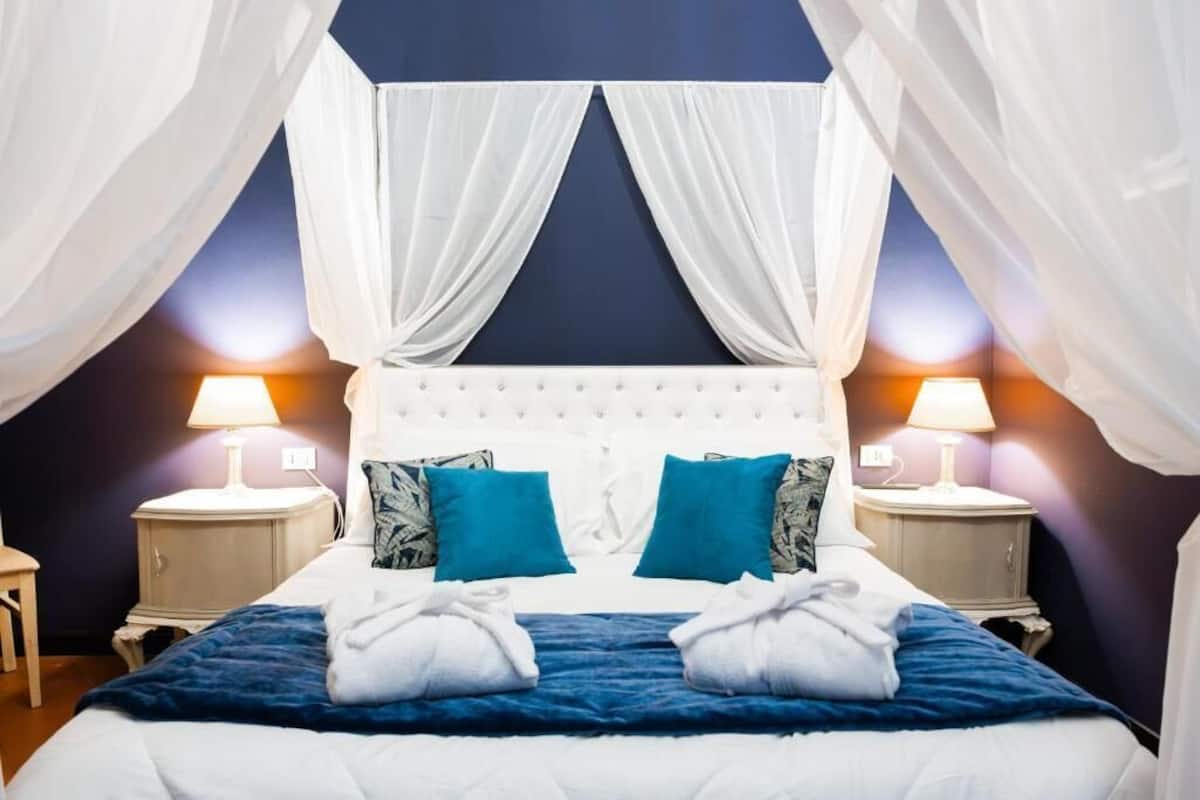 A bedroom with a canopy bed, two nightstands, and a blue bedspread.