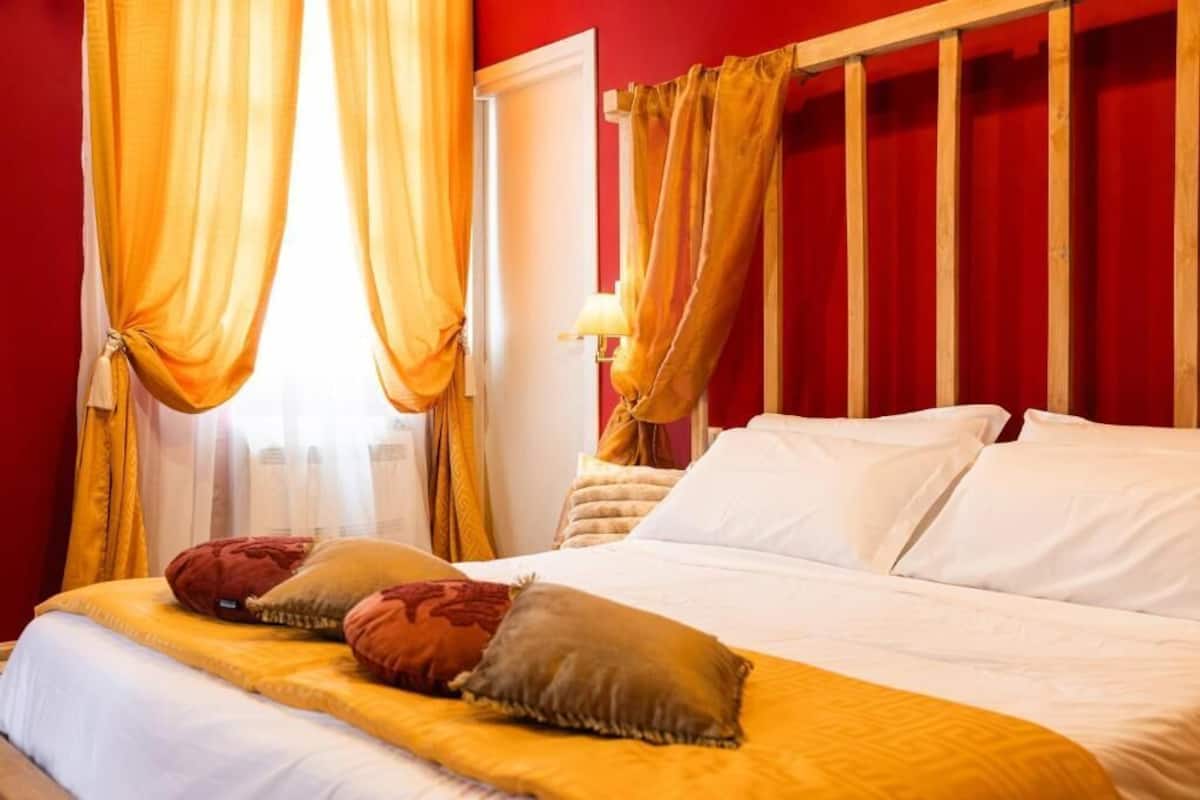 A hotel room with a bed, curtains, a nightstand, and a lamp.