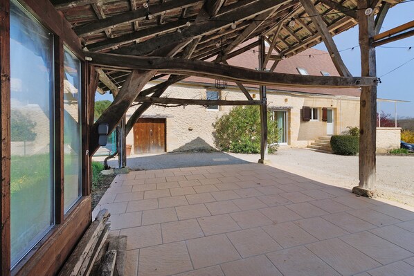 A covered patio area with a wooden ceiling and large windows.