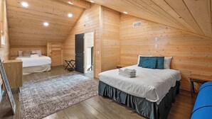A wooden cabin bedroom with a loft bed, a smaller bed, and a large window. - Lakefront - Private Dock - Near Ark - Sleeps 14 (Williamstown)