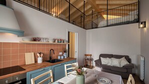 A kitchen with a wooden countertop, a sink, and a dining area with a table set for two. - Historic 1940s Watermill: A Designer Retreat in the Italian Alps (Cerete Basso)