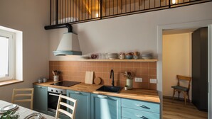 A kitchen with a wooden countertop, a sink, a stove, and a chair. - Historic 1940s Watermill: A Designer Retreat in the Italian Alps (Cerete Basso)