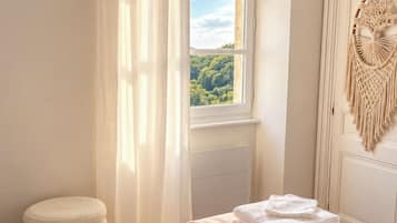 Une chambre à coucher comprenant un lit, une fenêtre, une table de chevet et un objet décoratif fixé au mur.