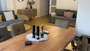 Ein modernes Wohnzimmer mit einem Holzesstisch, grauen Sofas und einem Deckenventilator.