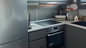 Eine moderne Küche mit grauen Schränken, einem eingebauten Backofen und einem Edelstahl-Kühlschrank.