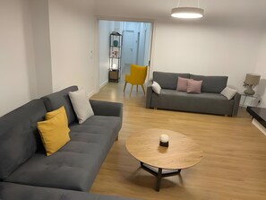 Ein modernes Wohnzimmer mit zwei Sofas, einem Couchtisch und einem Essbereich mit einem Stuhl.