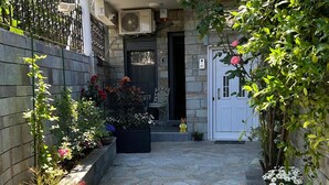 Un pati empedrat amb plantes en testos i una porta blanca.