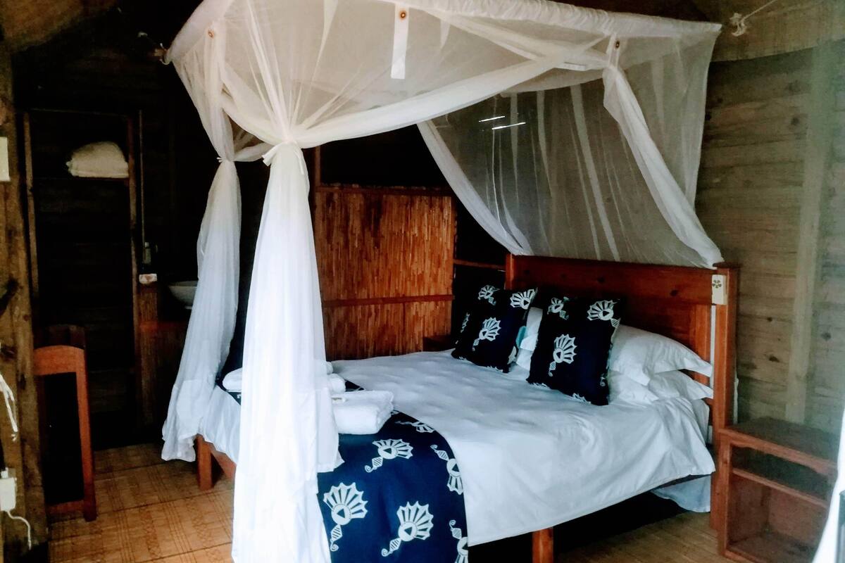 A single bed with a canopy, wooden headboard, and patterned bedspread.