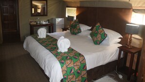 A hotel room with a large bed, a bedside table with a lamp, a mirror, and a small desk with a refrigerator. - Kosi Bay Mouth Utshwayelo Lodge and Camp (Mahlungulu)